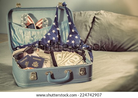 Travel Suitcase American Woman Vacation. Suitcase on a bed with women\'s clothes and an American theme with a vintage photograph filter.