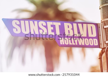 Sunset Blvd Hollywood Street Sign. A street sign marking Sunset Blvd in Hollywood, California. Backed by a palm tree with a sunset flare.