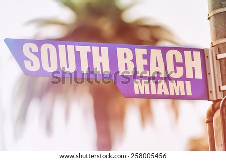 South Beach Miami Street Sign. A street sign marking South Beach, Miami. Backed by a palm tree with a sunset flare.