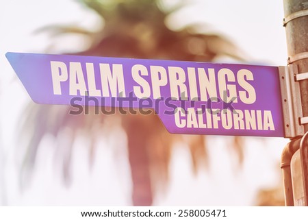 Palm Springs California Street Sign. A street sign marking Palm Springs, California. Backed by a palm tree with a sunset flare.