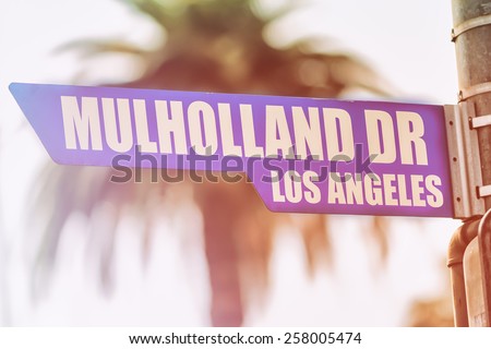 Mulholland Dr Los Angeles Street Sign. A street sign marking Mulholland Dr, Los Angeles. Backed by a palm tree with a sunset flare.
