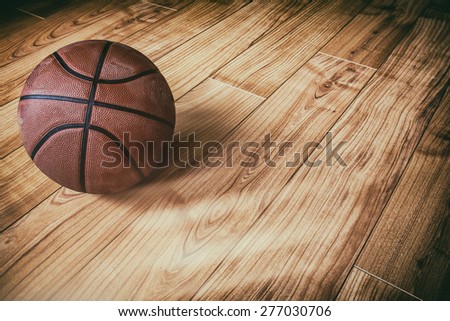 Basketball on Hardwood 3. A basketball laying on the ground of a hardwood court in a gymnasium.
