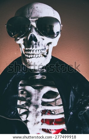 Cool Skeleton Heart. A cool skeleton wearing a leather jacket and sunglasses, with a smoke in his mouth. His heart visible in his ribcage. Edited in vintage film style.