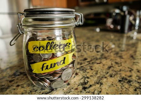 College Fund Money Jar. A clear glass jar filed with coins and bills, saving money. The words \