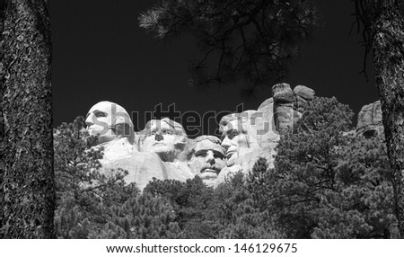 Black and white image of Mount Rushmore through the trees