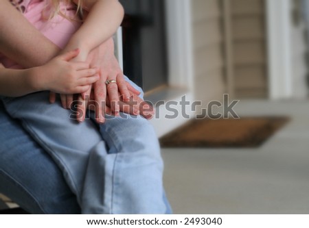 Hands of a mother and daughter on top of each other, sitting on a porch. Shallow Depth of Field