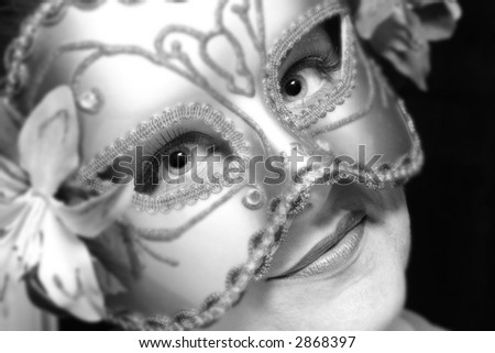 Portrait of a beautiful young woman wearing carnival mask in black and white