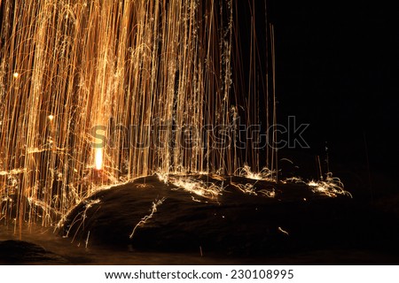bright yellow festive fire works with sparks falling down on stones and into water