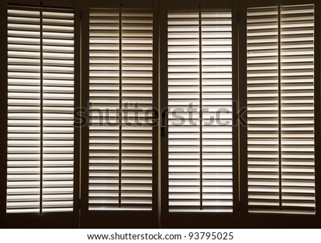 Wooden shutters in front of bright, sunlit windows