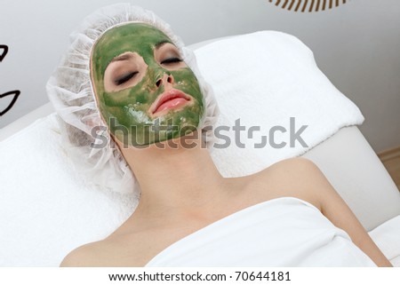 Closeup of beautiful woman, resting with clay mask on her face.