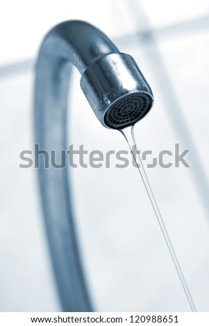 Water tap with flowing water. Selective focus, shallow depth of field