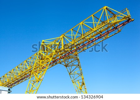 Yellow gantry crane over bright blue sky
