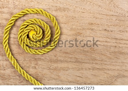 Twisted gold rope on wooden background