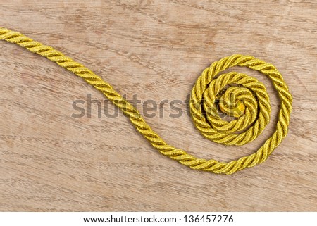 Twisted gold rope on wooden background