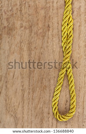 Twisted gold rope on a brown wooden background