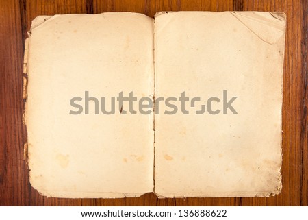 Old opened softcover book with yellowed pages on a wooden background