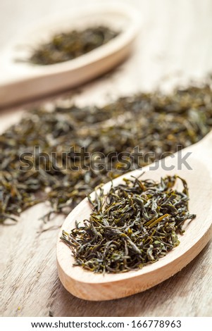 Wooden spoons with green tea herbs. Shallow depth of field