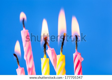 Burning birthday candles over blue background. Shallow depth of field