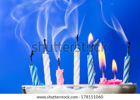 Burning and extinct birthday candles over blue background. Shallow depth of field