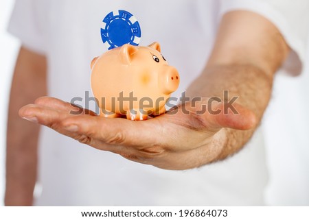 Piggy bank with poker chip on back hold by man hand