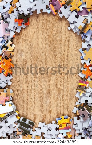 Frame of jigsaw puzzle pieces on wooden background