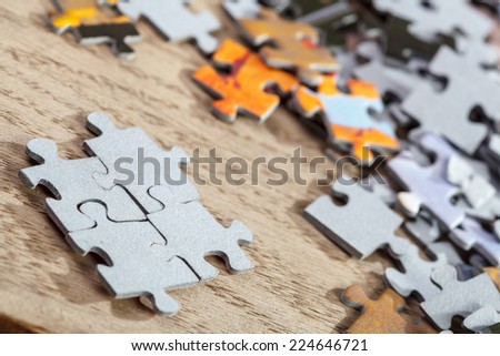 Closeup of  four connected jigsaw puzzle pieces on a table. Shallow depth of field