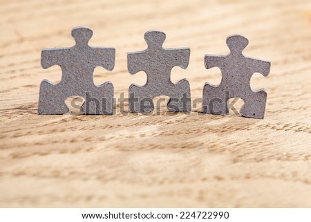 Concept of teamwork: Three jigsaw puzzle pieces on a table. Shallow depth of field