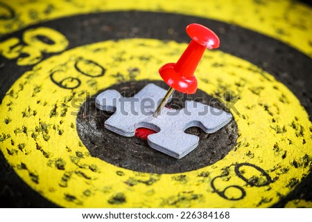 Targeting customers concept: red pin stuck to a man shape jigsaw puzzle piece on old target board