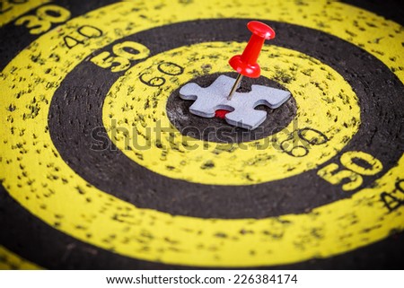 Targeting customers concept: red pin stuck to a man shape jigsaw puzzle piece on old target board