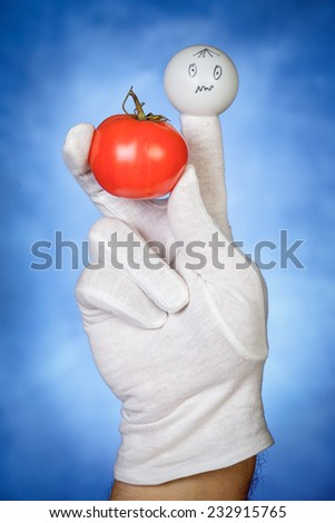 White finger puppet holding tomato fruit with confused face expression