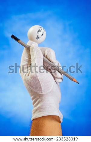 Happy finger puppet with sharp pencil over blue background