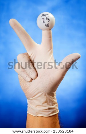 Hand in white latex glove with smiling face finger puppet over blue background