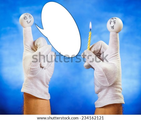 Happy finger puppet with speech bubble receiving burning candle from other smiling finger puppet over blue background