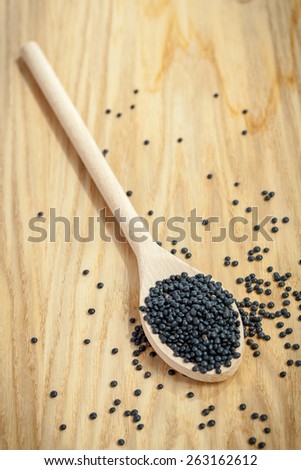 Wooden spoon on board and black lentils. Shallow depth of field