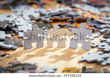 Three paper jigsaw puzzles surrounded by pieces  on a table. Shallow depth of field
