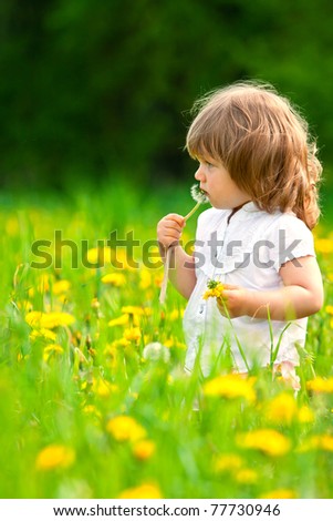 Little girl in a dandelion meadow putting dandelion in the mouth