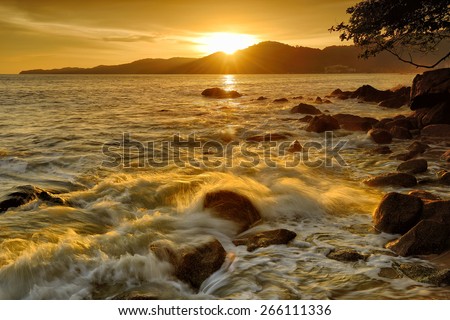 Golden Wave splashing on the rock under the sunset sky
