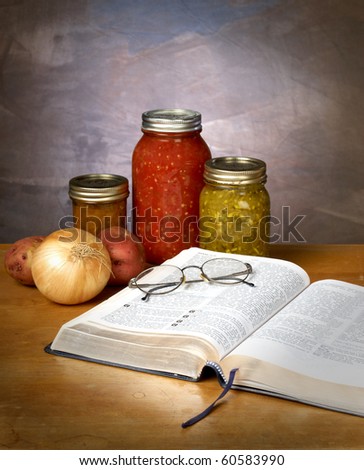 FOOD FOR THOUGHT - canned vegetables and fruit with a bible and pair of glassed on a kitchen counter