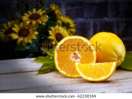 Oranges on wood table top with sunflowers in background Studio Shot Soft focus