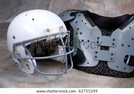 Football helmet and shoulder pads on tan background
