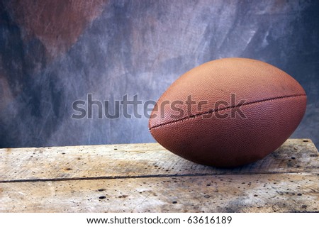 Football on old ages wood table and studio tan and blue back drop with copy space
