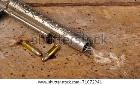 Smoking gun and bullets on old vintage wood table with copy space
