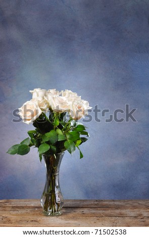 White Roses on a rustic old vintage table with blue background and copy space