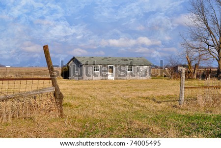 Old vintage chicken Barn with blue sky and clouds and pasture