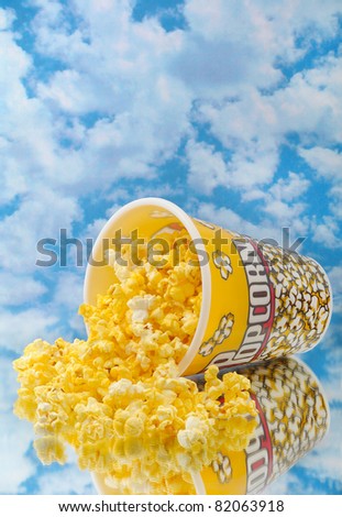 Popcorn on glass with cloud background and container