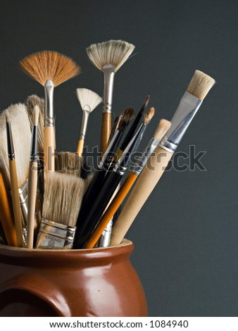 Artist brushes in a pot, on a dark grey background