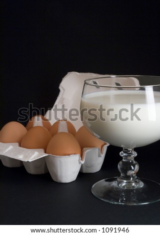 Six eggs in a box and a glass of milk, over a black background
