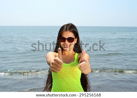 Beautiful Asian lady standing on the beach with thumbs up sign
