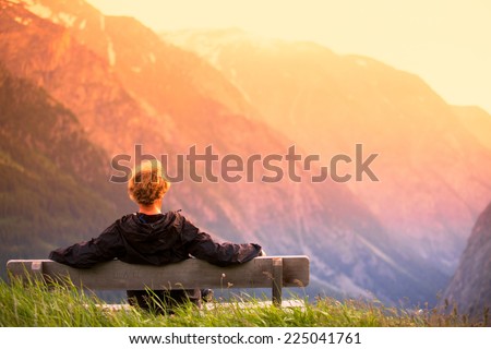 man on bench in high mountains