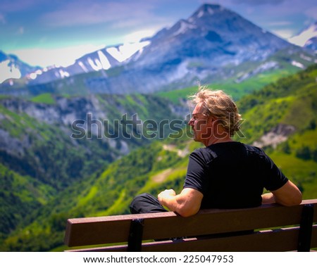 Man on bench in mountains daytime
